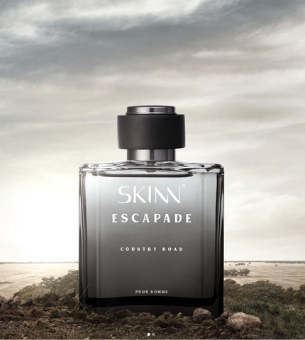 A Skinn Escapade Country Khad perfume bottle displayed on a beach background.